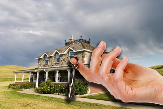 A hand holding a skeleton key in front of an old masion.