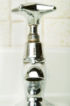 A retro sink tap and faucet with drip caught in motion.