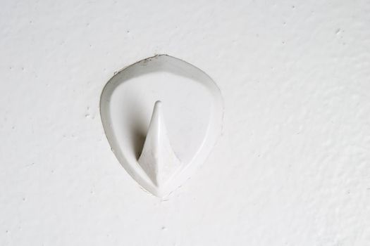 A retro bathroom hook stuck on the wall from the 1970's era.