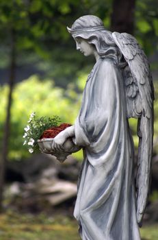 A statue of an angel holding a bed of flowers.