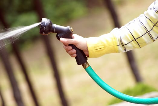 A woman uses the hose while she's outside.