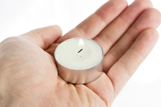 A simple tea light candle being held in a hand, isolated on white with clipping path.
