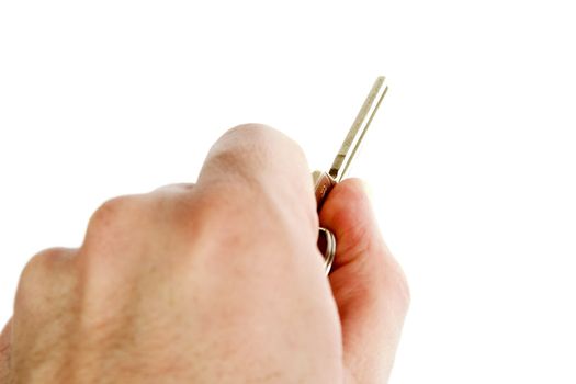 A standard house key being held in a male hand.  Isolated on white with clipping path.
