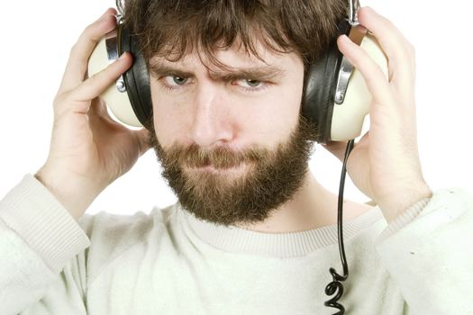 A young man looking sceptical while listening to music on headphones.  Isolated on white with clipping path.