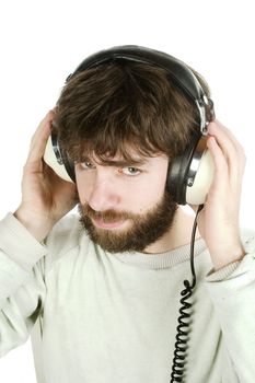 A young man looking sceptical while listening to music on headphones.  Isolated on white with clipping path.