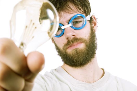 A concept image protraying a funny / good idea.  A young funny looking bearded male with swimming goggles holding up a light bulb.