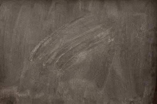 blank blackboard with a lot of white chalk dust and smudges from eraser