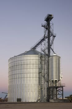 newly constructed metal grain silo and elevator against clear sky