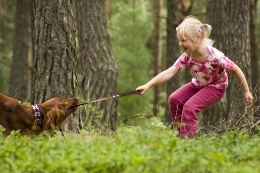little girl playing with her dog in the forest