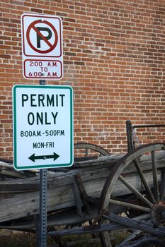 no parking, permit only sign and old wooden wagon against old brick wall