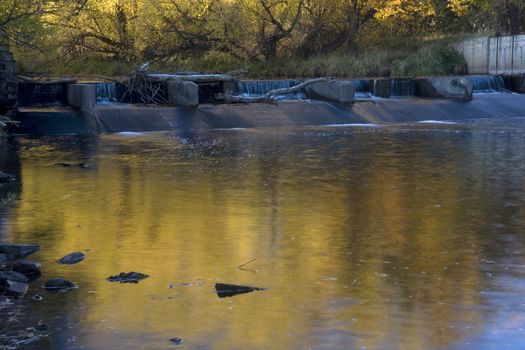 One of the diversion dams on Cache la Poudre River  in Colorado near Fort Collins supplying water for farmland irrigation, fall scenery with gold foliage and low flow.