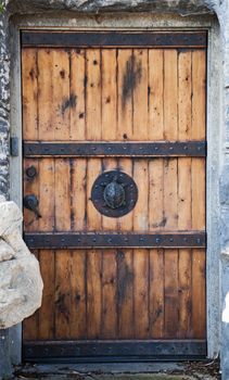 Old reinforced wood door with a turtle door knob and metal braces