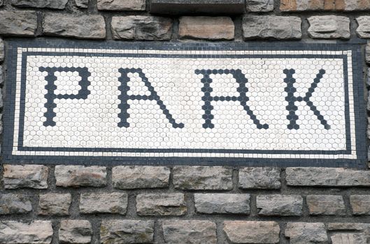 an old brick wall with a park sign set in the wall
