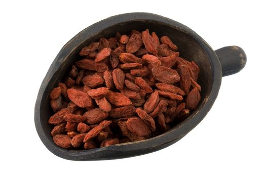 dried Tibetan goji berries (wolfberries) on a primitive, wooden, dark painted scoop, isolated on white