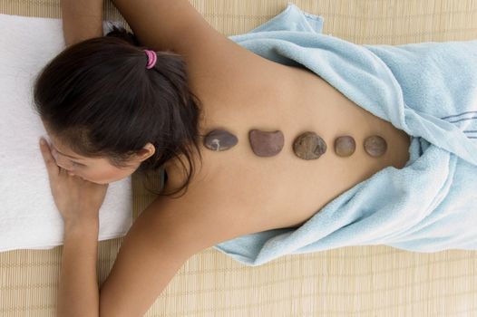 high angle view of laying young woman taking stone therapy