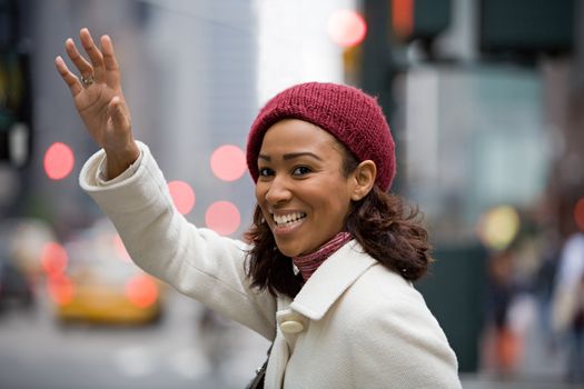 A pretty young business woman hails a taxi cab in the city.