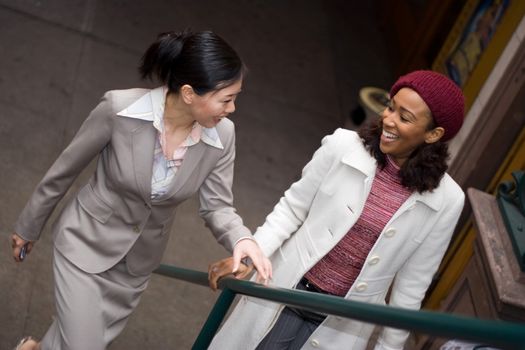 Two business women having a casual meeting or discussion while walking in the city.  