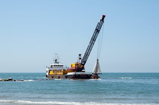 A barge is dredging a harbor removing stones and sand