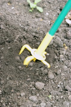 A closeup shot of a hand tiller working the dirt around with a motion blur to add effect.