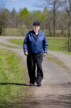 Elderly man walking on country road