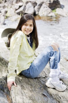 Girl sitting on rock cliff edge over river