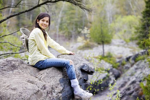 Girl sitting on rock cliff edge over river