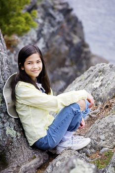 Girl sitting on rock cliff edge over river