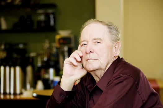 Elderly man in coffee shop, sitting alone at a table