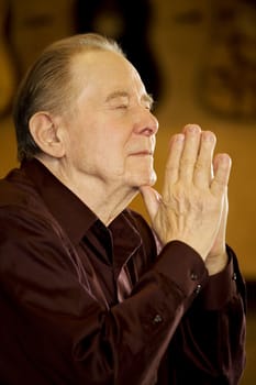 Elderly man praying in dark church