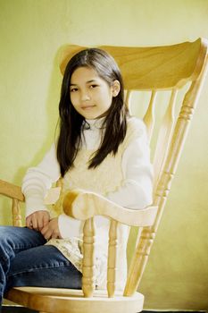 Girl in rocking chair looking out window, thoughtful look