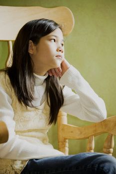 Girl in rocking chair looking out window, thoughtful look