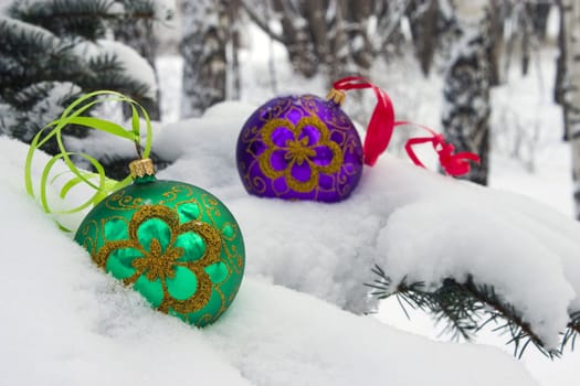 Two color christmas baubles sitting in a bed of snow.
