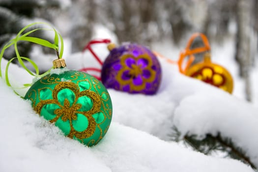 Three color christmas baubles sitting in a bed of snow.