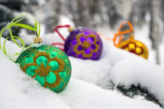 Three color christmas baubles sitting in a bed of snow.