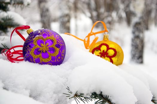 Two color christmas baubles sitting in a bed of snow.