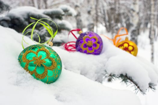 Three color christmas baubles sitting in a bed of snow.