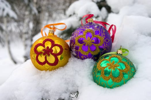 Three color christmas baubles sitting in a bed of snow.
