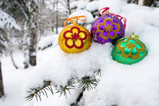 Three color christmas baubles sitting in a bed of snow.