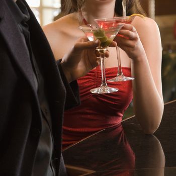 Taiwanese mid adult woman and Caucasian man toasting martinis.