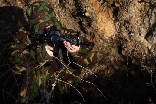 A soldier holding a M16 (AR-15) Rifle with camouflage and a balaclava.