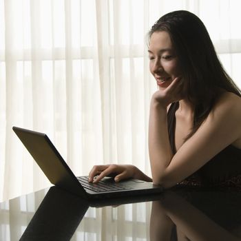 Taiwanese mid adult woman on laptop smiling.
