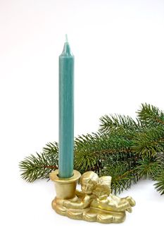 Green candle in angel candleholder with fir branch on light background
