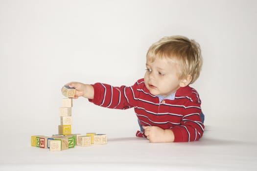 Studio portrait of Caucasian boy playing with toy blocks.