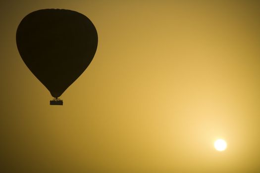 A hot air Balloon backlit by the rays of the morning Sun.