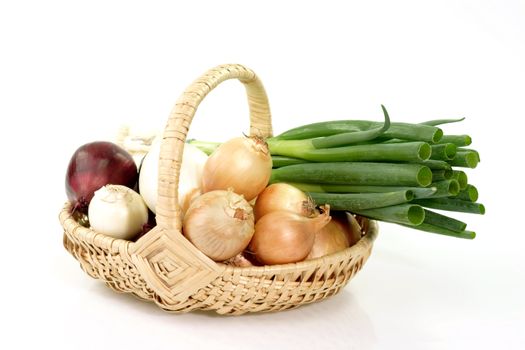 Different sorts of onions in a basket on bright background