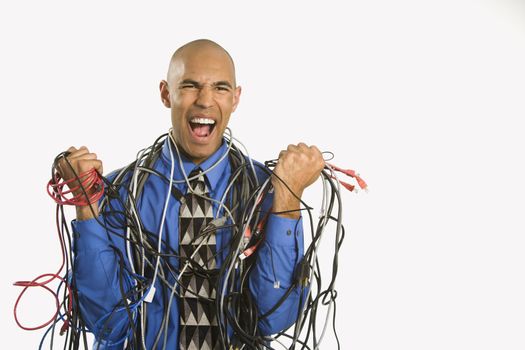 African American businessman wrapped in computer cables screaming.