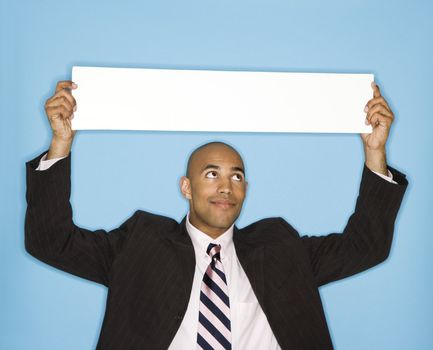 African American man holding blank sign against blue background.