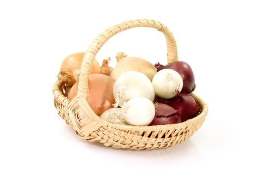 Different sorts of onions in a basket on bright background