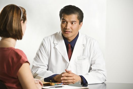 Asian American male doctor consulting with Caucasian female patient.