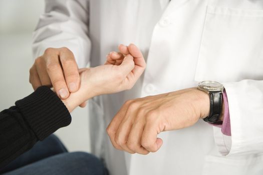 Doctor taking patient's pulse.